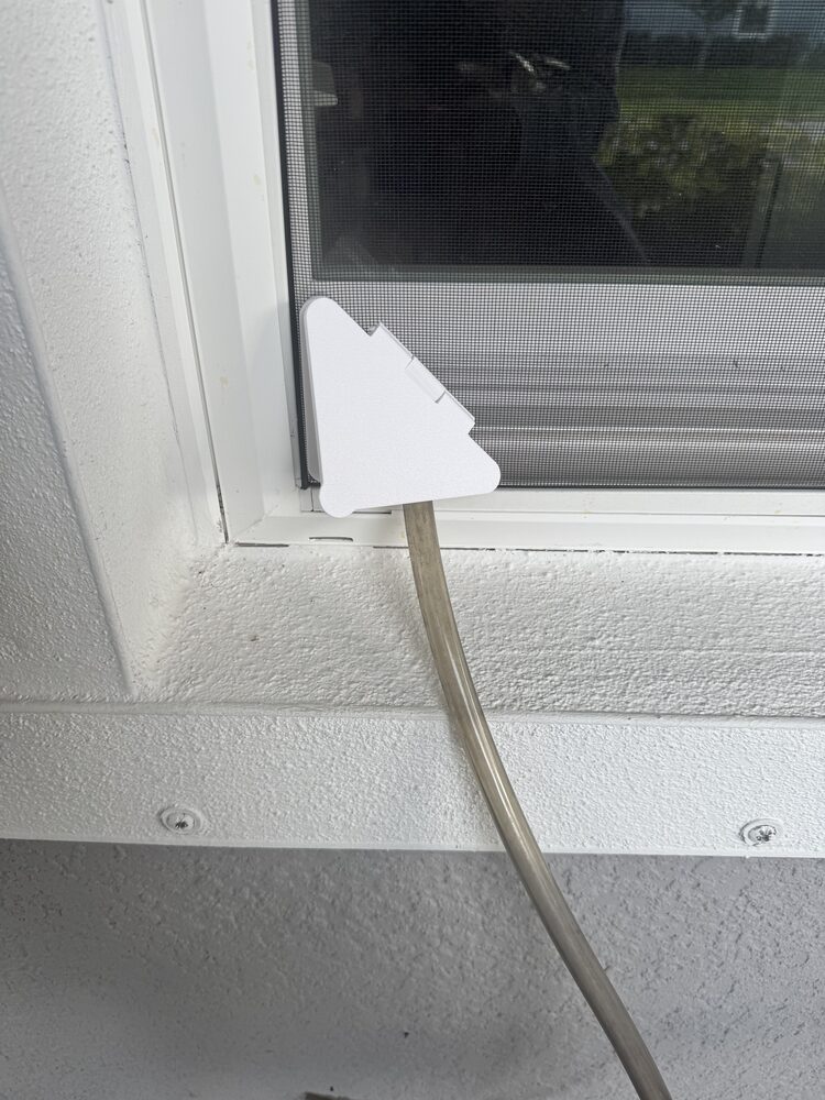 Magnetic Screen Pass-Thru installed on a window screen with a hose running through it